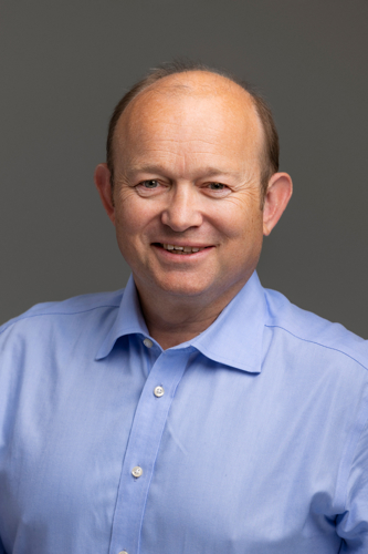 Portrait of a man smiling wearing a light blue shirt.